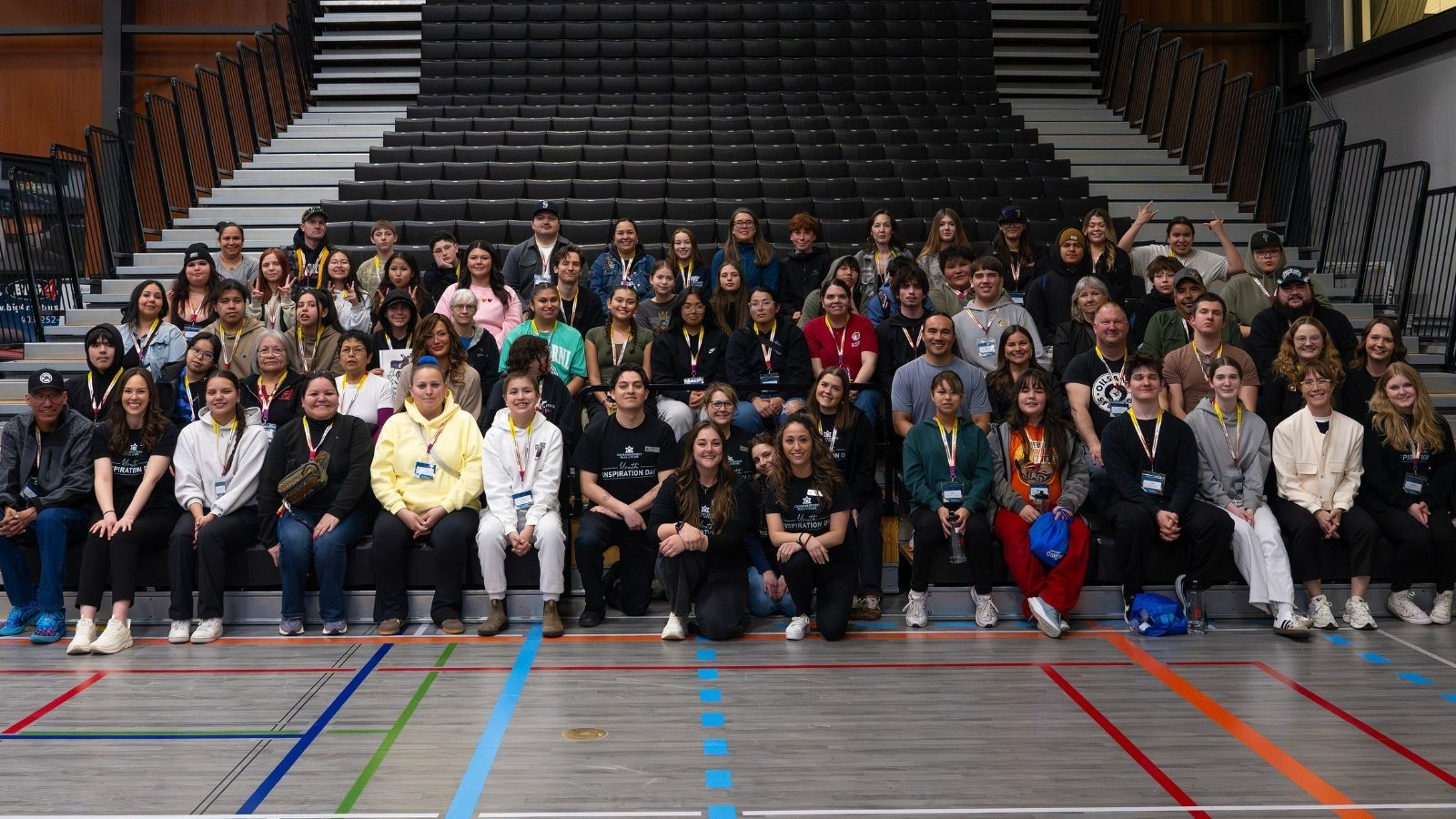 Indigenous youth from the 2026 Youth Inspiration Day sit on gymnasium risers
